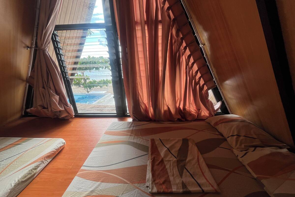 Una habitación con cama, vista a una piscina y cortinas.