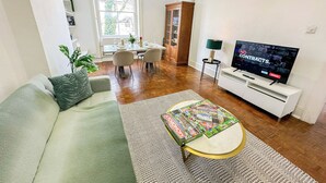 Un salon comprenant un canapé, une table basse, un téléviseur, un coin repas et une vue sur l’extérieur.
