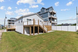 Une maison à deux étages dotée d’une terrasse et d’un escalier menant à un balcon situé au deuxième étage.