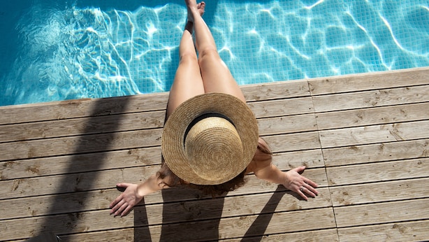 A wooden deck with a pool in the background.