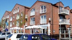 A multi-story brick building with balconies and a restaurant on the ground floor. - Apartment Raum in Fehmarn Orth (Fehmarn)