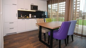 A modern kitchen with white cabinets, a wooden table, and purple chairs. - Reihenhaus Reiterchalet in Wendorf (Kuhlen-Wendorf)