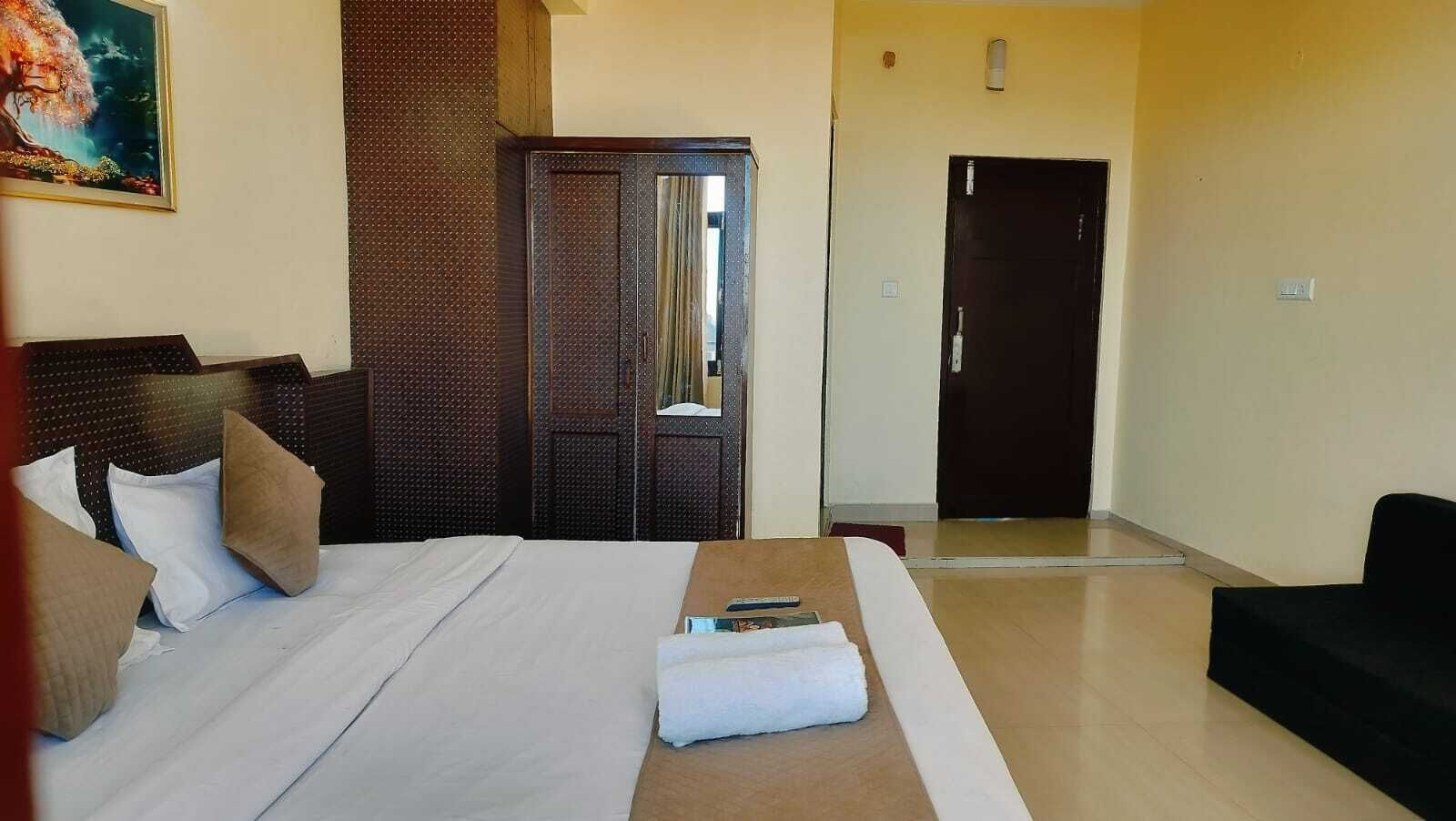 A hotel room with a large bed, a wardrobe, a mirror, and a door.