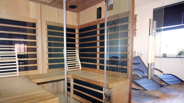 Een kamer met een houten vloer, een glazen scheidingswand en een stoel.
