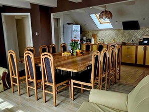 Enjoy meals in the dining area with a large table and matching chairs, a modern kitchen with oven, and a flat-screen TV.