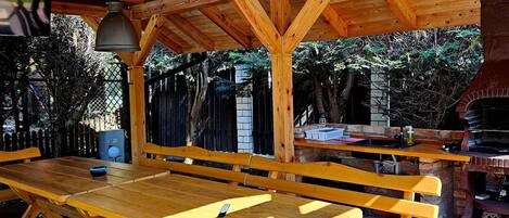 An outdoor wooden deck with picnic tables and a brick barbecue area.
