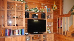 Een houten entertainmentkast met een flatscreen-tv, omringd door boeken, decoratieve voorwerpen en een kleine speaker.