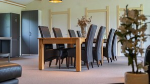 A dining area with a wooden table and chairs, a refrigerator, and pendant lights. - Pet Friendly & Peaceful Stay (Beesel)