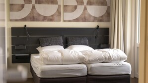 A double bed with white bedding, a dark headboard, and two black and white pillows. There are abstract wall art pieces above the bed. - Pet Friendly & Peaceful Stay (Beesel)