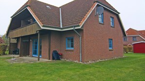 Une maison à deux étages, construite en briques, avec un toit en pente, une antenne parabolique et un garage.