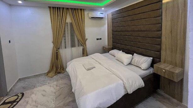 Un dormitorio moderno con cama, cortinas y cabecero de madera.