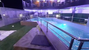 Una piscina con un deck circundante, escalones que bajan a la piscina y un nivel superior cubierto con asientos.