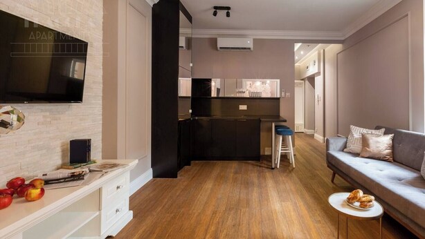 A modern apartment with a kitchen, living area, and a TV mounted on the wall.