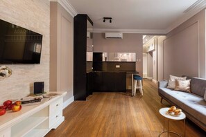Een modern appartement met keuken, woonruimte en een aan de muur bevestigde televisie.