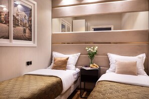 Ein Hotelzimmer mit zwei Betten, einem Nachttisch, einem Spiegel und einem Fenster mit Blick auf die Stadt.
