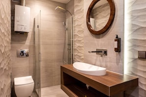 Un baño moderno con ducha, inodoro y tocador con lavamanos.
