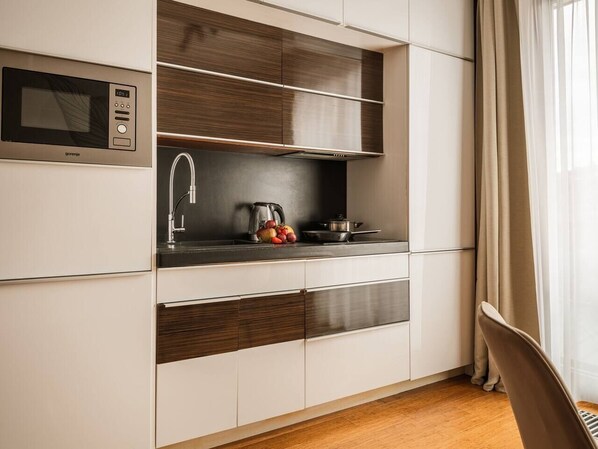 A compact kitchen with a microwave, sink, and wooden cabinets.
