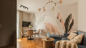 Una sala de estar moderna con sofá, mesa de centro y comedor con sillas y televisor.