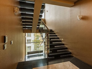 Interior moderno com escada, guarda-corpo de vidro e vista para o exterior.