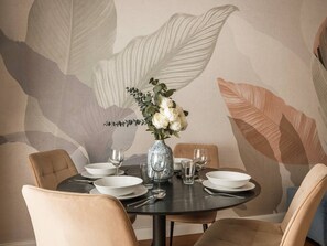 Une table à manger ornée d’un vase de fleurs, de assiettes blanches et de verres.
