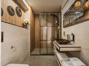A modern bathroom with a glass shower enclosure, a wooden vanity with a vessel sink, and a large mirror.