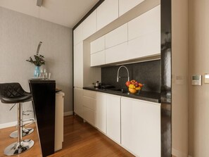 Een moderne keuken met witte kastjes, een zwart aanrecht, een roestvrijstalen spoelbak en een fruitschaal.