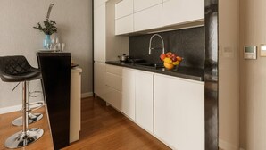 Cocina moderna con alacenas blancas, encimera negra, pileta de acero inoxidable y un frutero.