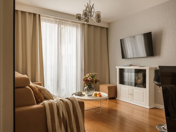 Ein modernes Wohnzimmer mit einer Couch, einem Couchtisch mit Blumen, einem Fernseher und einem Schrank.