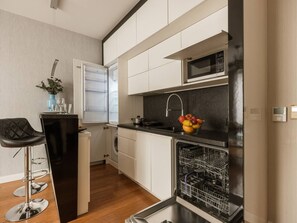 A compact kitchen with a microwave, sink, and dishwasher.