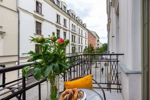 A balcony with a table, a vase with flowers, and a railing.