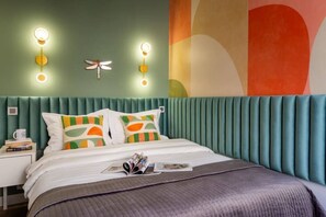 A bed with a teal upholstered headboard, two pillows with geometric patterns, and a magazine on the bed.