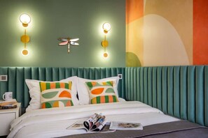 A bed with white bedding, two pillows with geometric patterns, a nightstand with a cup, and wall-mounted lights.