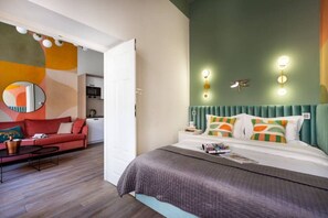 Ein modernes Hotelzimmer mit Bett, Sofa, Essbereich und einer Küche im Hintergrund.