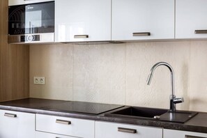 A kitchen with a Bosch microwave, a sink with a modern faucet, and white cabinets.