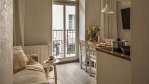 Een gezellige woonkamer met een bank, een kleine tafel met een boek en een kopje, en uitzicht op het balkon.