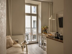 A cozy living room with a sofa, a small table with a book and a cup, and a view of the outside balcony.
