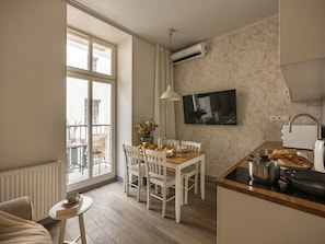 A modern kitchen with a dining area, a large window, and a flat-screen TV.
