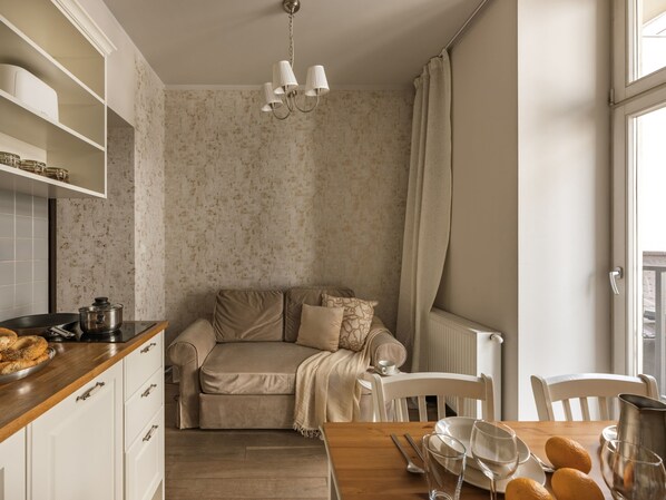 Una kitchenette acogedora con encimera de madera, horno empotrado y comedor con mesa lista para dos.