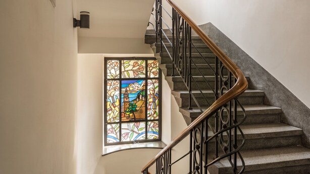 A staircase with a handrail and a stained glass window at the bottom.