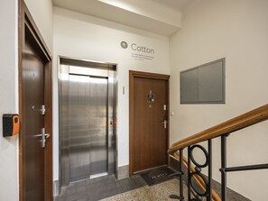 Un vestíbulo de hotel con ascensor, una puerta de madera, un cartel en la pared y una barandilla.