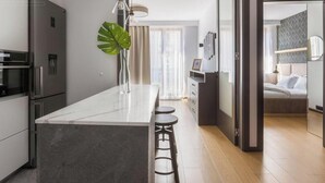 Une cuisine moderne avec un îlot en marbre, des tabourets de bar et une grande plante.