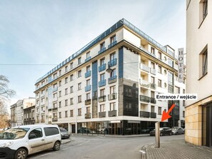 Un hotel de varios pisos con diseño moderno, que presenta una entrada destacada con fachada de vidrio y un letrero que indica la ubicación.