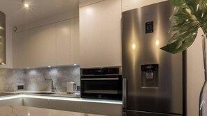 Une cuisine moderne dotée d’un plan de travail en marbre, d’appareils électroménagers en acier inoxydable et d’un distributeur d’eau.