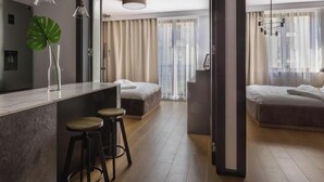 Une chambre d’hôtel moderne dotée d’un coin cuisine, d’un espace repas et d’un grand lit.