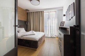 A modern bedroom with a bed, a wardrobe, a window with curtains, and a wall-mounted picture.