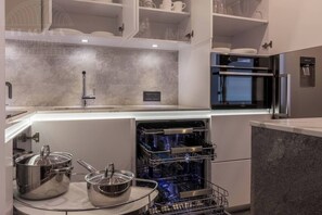 A modern kitchen with a built-in dishwasher, stainless steel appliances, and a marble countertop.