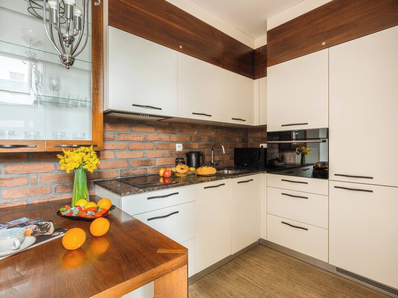 Una cucina moderna con mobili bianchi, una parete di mattoni a contrasto e un piano di lavoro in legno.