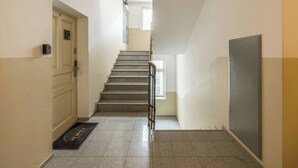 Un passadís amb una escala, una porta, un detector d'incendis i una finestra.