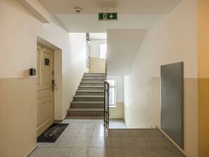 En gang med trappe, en dør, en brandalarm og et vindue.