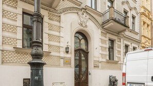 Un edifici amb una entrada destacada, un pal metàl·lic i una furgoneta estacionada.